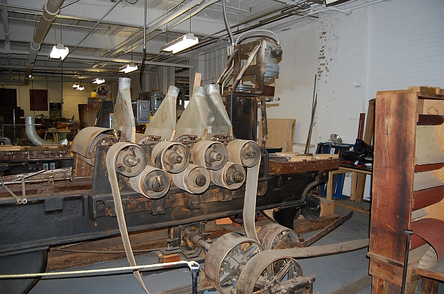 Surfacing machine to prepare and smooth maple sections cut from the tree prior to carving the face.  Note the four drums of successively finer grits of sandpaper.