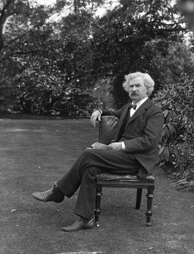 Samuel Clemens / Mark Twain seated outdoors.
