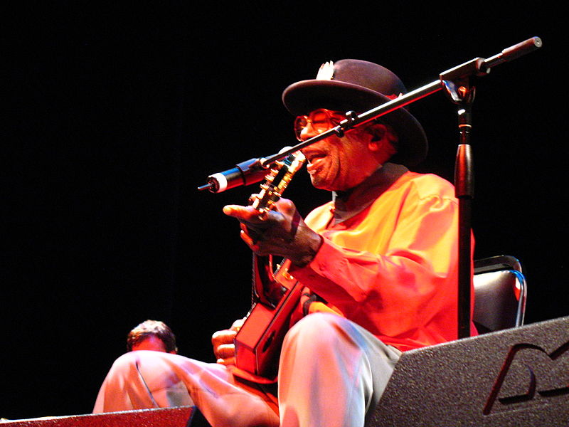 Bo Diddley singing and playing guitar.