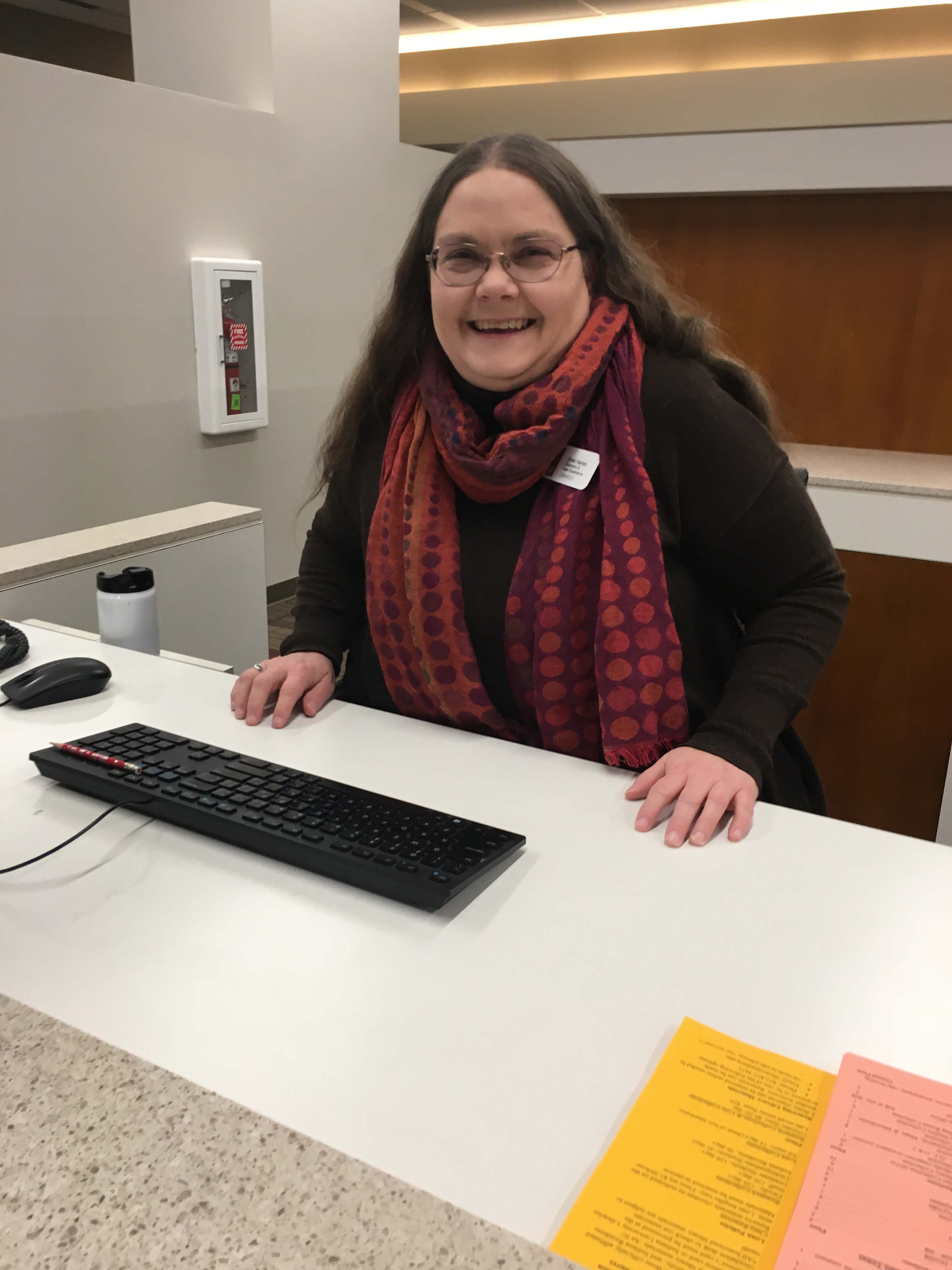 Photograph of Anne Haines smiling behind the IU Libraries reference desk. 