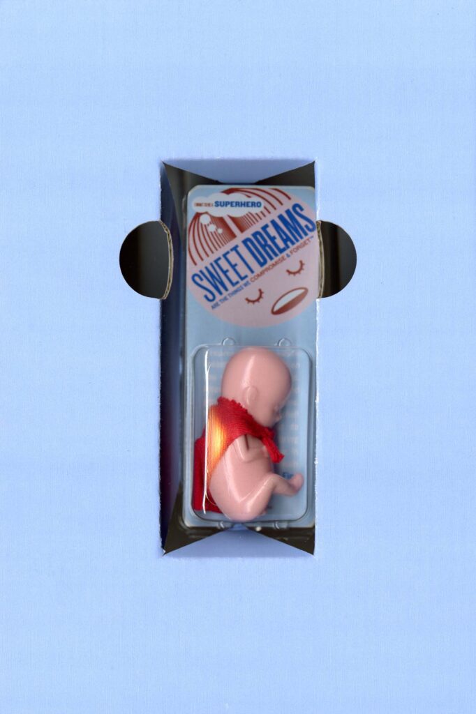Small plastic fetus collectible with a tiny red superhero cape
