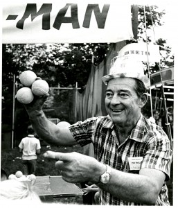  Black and white photograph of a man holding three tennis balls in one hand.