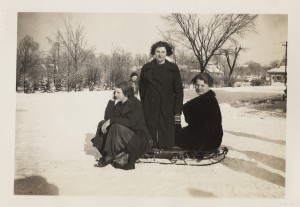  Black and white photograph of several female students sitting on a sled. 