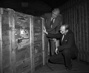  Black and white photograph of two men examining a wooden crate. 