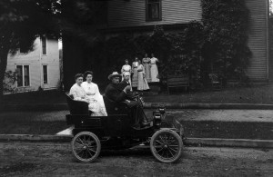  Black and white photograph of a family riding in an open-top car.