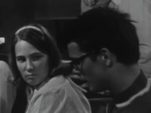  Still image from a black and white film of a woman and man in conversation 