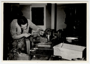  Black and white photograph of a student working on a machine. 