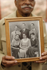 Leon "Parker" Taylor holds the only photograph his family could locate of his mother, seated bottom middle surrounded by her children.  Parker is the young gentleman in the upper left corner. Photo courtesy Eric Rudd, Indiana University.