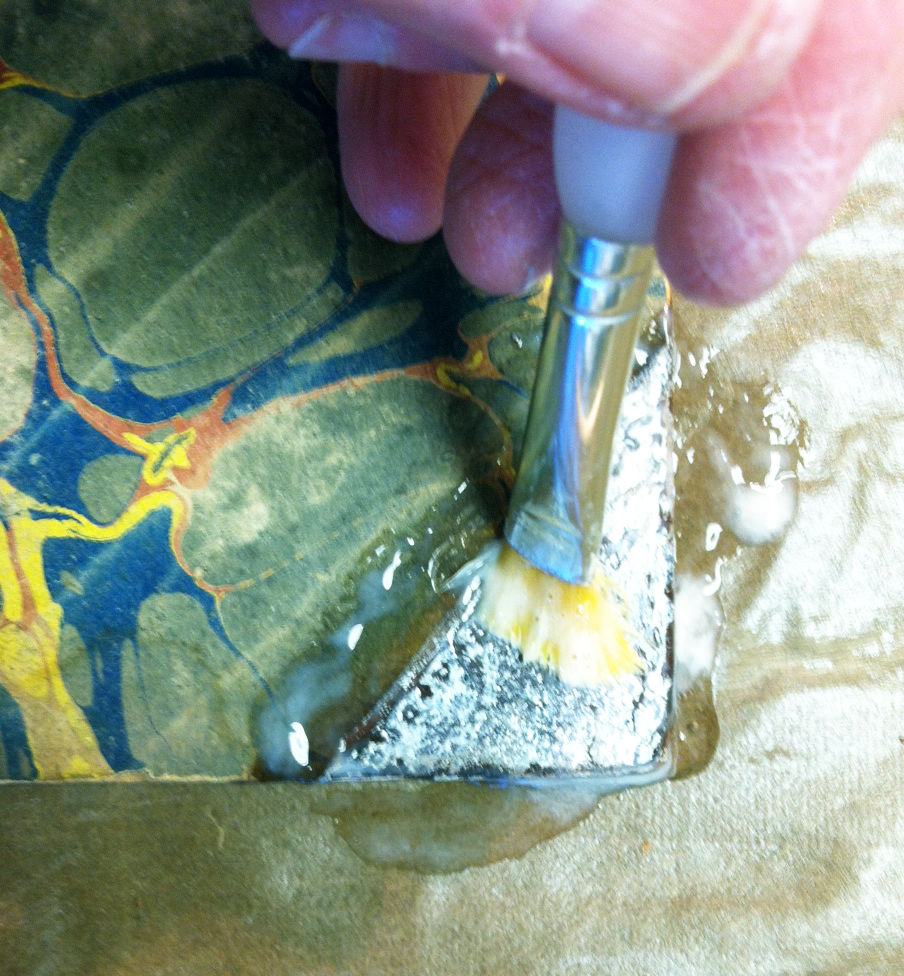 Close up of the tape adhesive removal process using a soft paint brush and Klucel G
