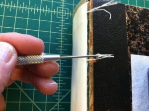 Using a needle awl to fray out threads to be used to reattach book covers