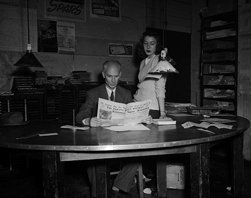Black and white photograph of Ernie Pyle and Patricia Krieghbaum in the IDS office, November 1944