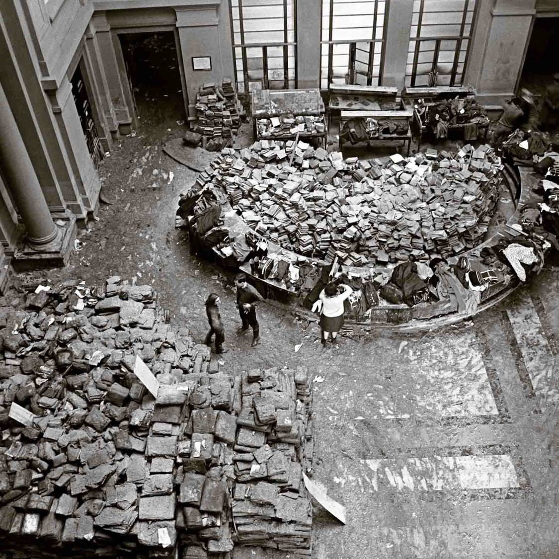 Black and white photograph showing an overhead shot of people assessing flood damage in a museum.