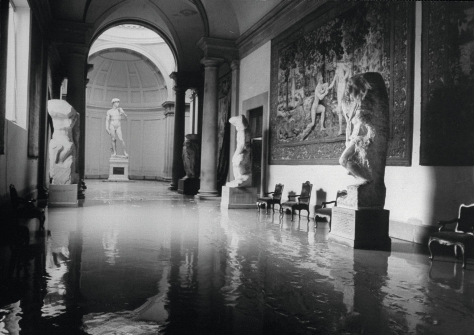 Black and white photograph of a flooded museum hall showing statues and paintings.