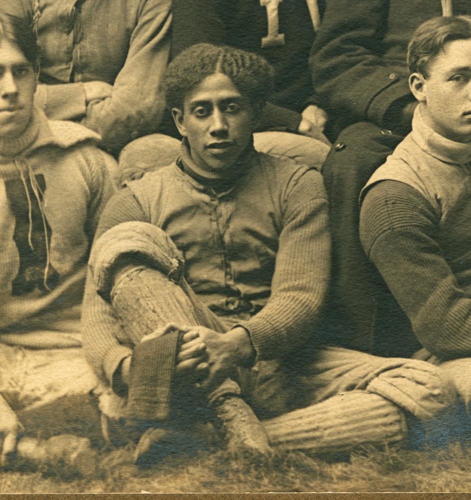 Black and white photograph of a seated football player. 