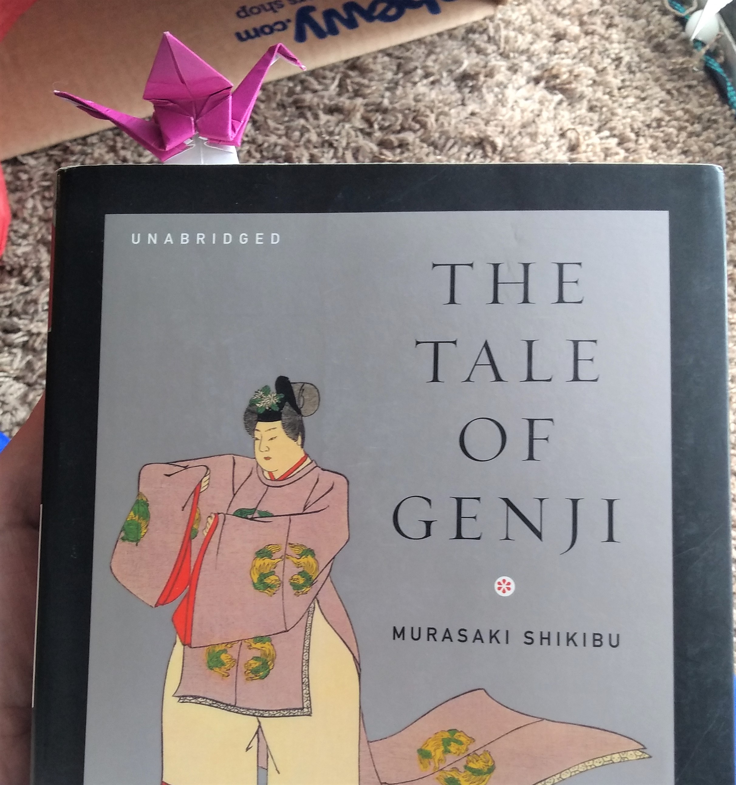 A pink origami crane bookmark inserted in The Tale of Genji.