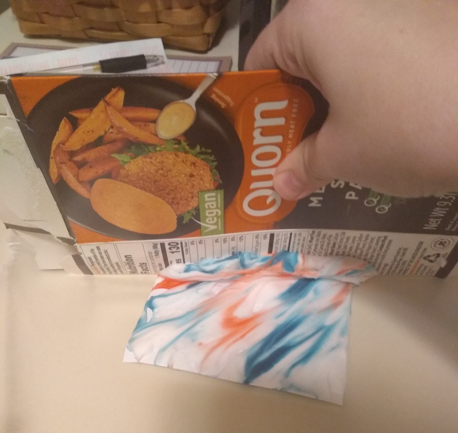 Scraping shaving cream off the paper with a piece of cardboard.
