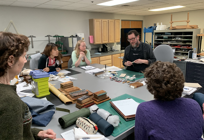 Jeff Peachey leading a discussion on conservation of leather bindings around a lab table in the Conservation Lab at the University of Notre Dame.