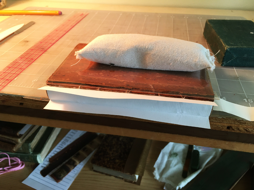 View of the spine area of the book with a piece of paper glued to it, the first step to forming a holow tube.