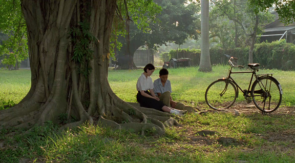 still image of a boy, girl, and bicycle in the park from the movie, A Brighter Summer