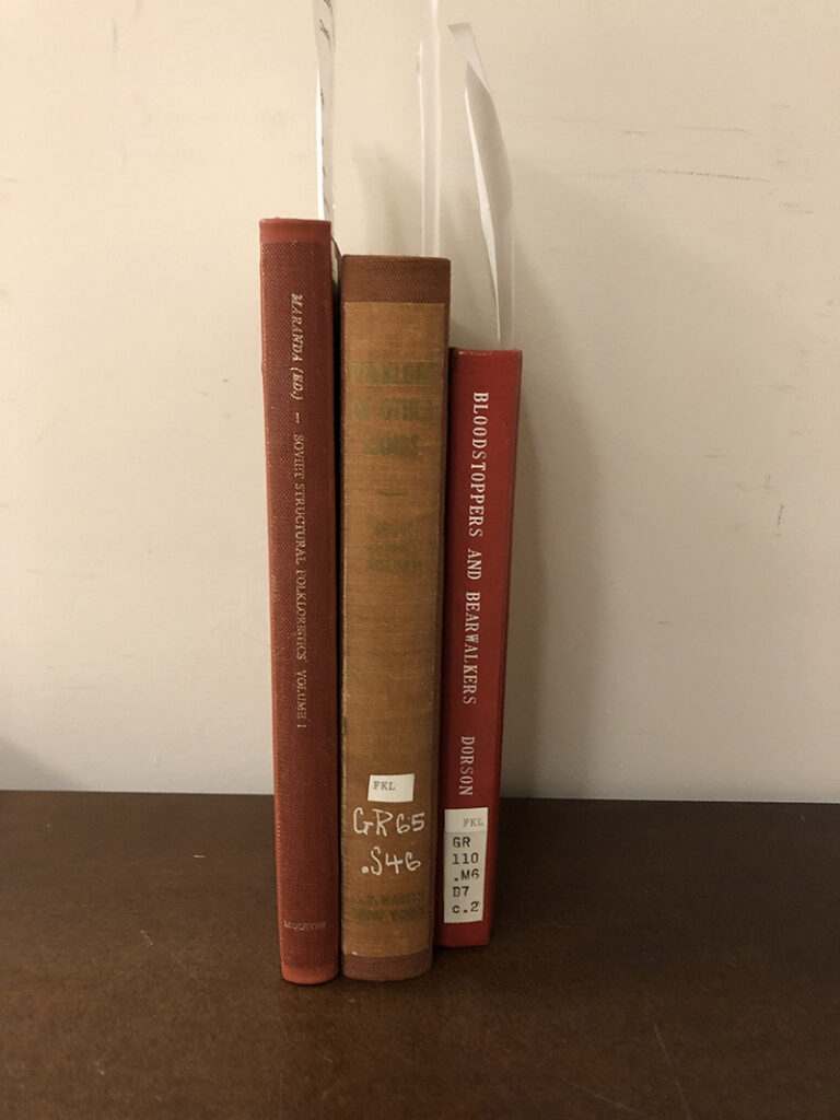 Three books after they were repaired, standing with spines showing.