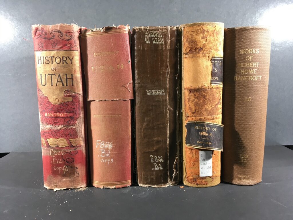 Five copies of the history of Utah, each with different covers, binding methods, and damage.