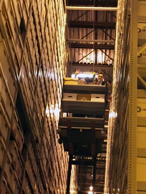 People on a lift vehicle used to retrieve and shelve materials in the Ruth Lilly Auxiliary Library Facility at IU.