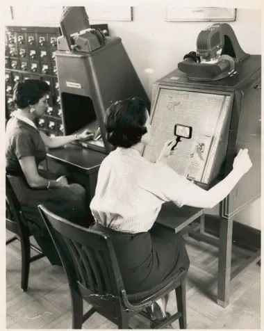 Two people using microfilm readers