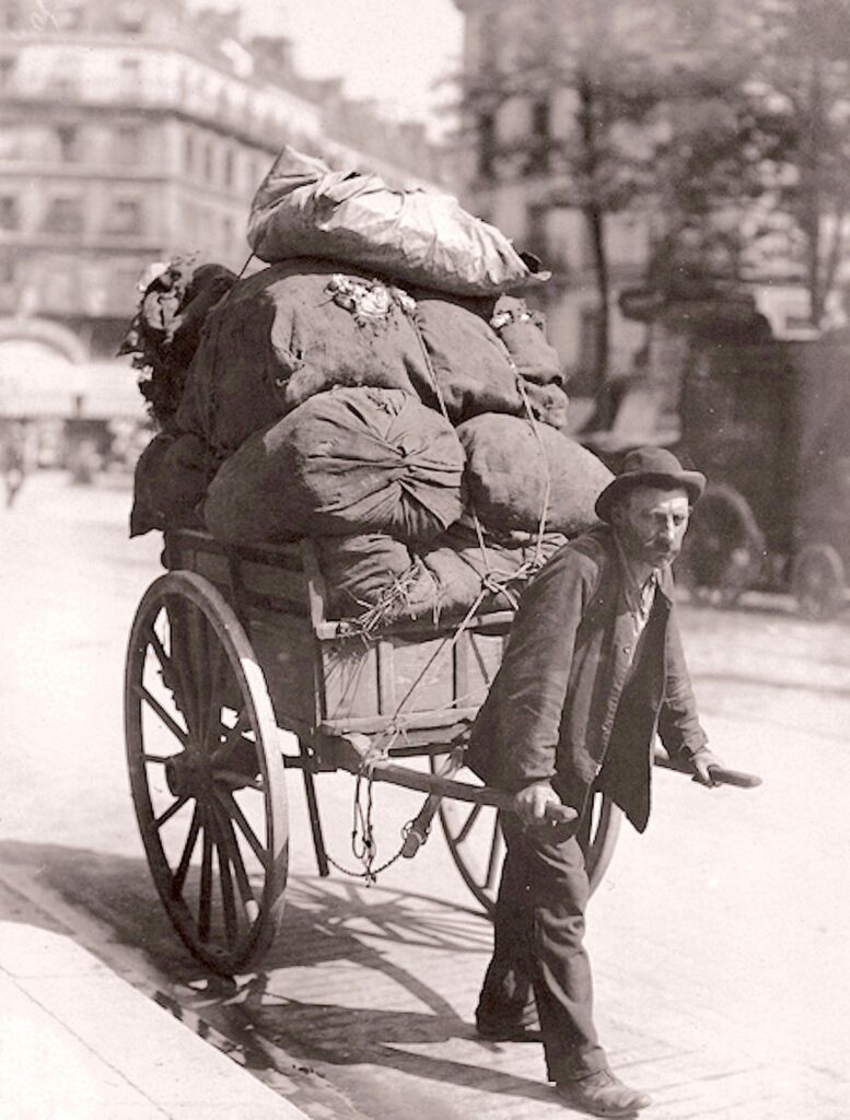 Photograph of a 19th century rag collector pulling his cart of bundled rags through the streets of Paris.