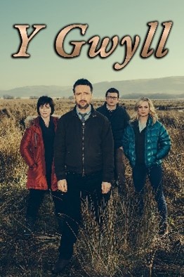 Four people in coats stand together facing the viewer, in a field with hills in the background. The series title, "Y Gwyll" is printed above.