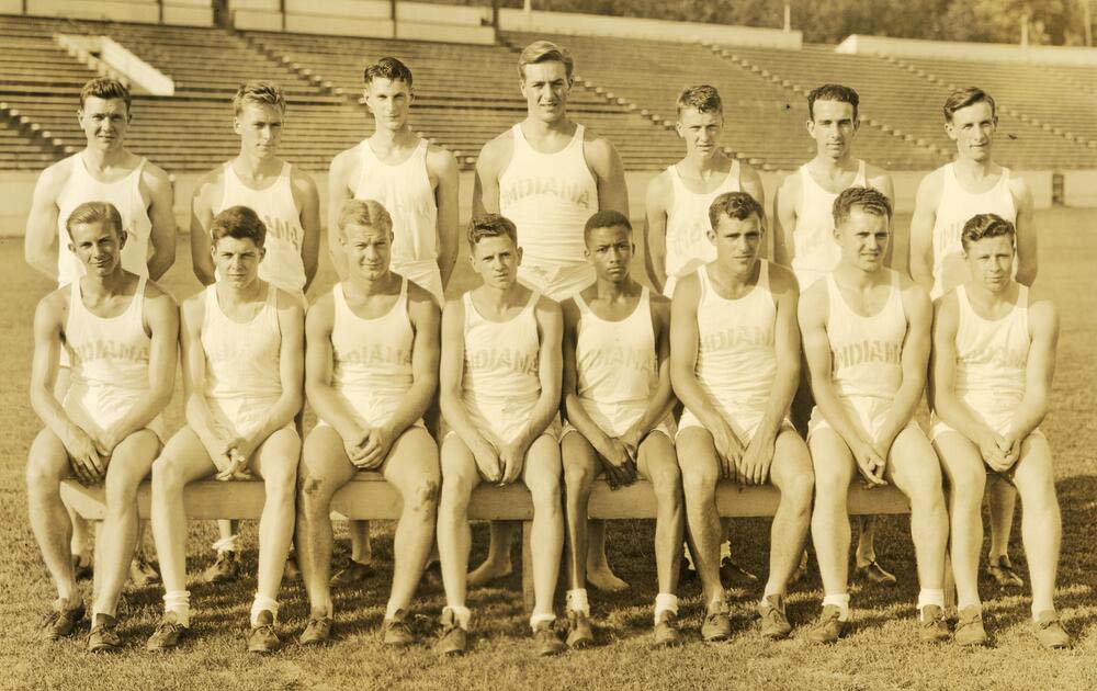 1936 Black and white photograph of 15 members of the cross country team wearing running uniforms