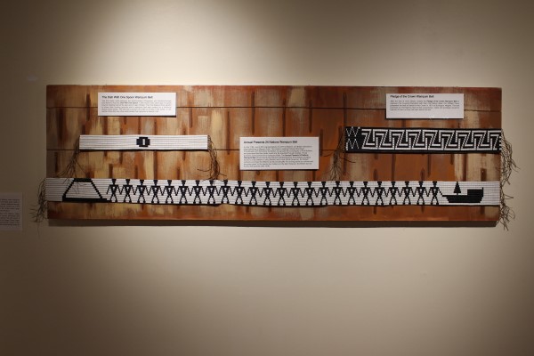 Exhibit of Wampum belt on a wooden board against a cream-colored background