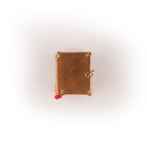 A miniature book with a brown leather cover and gold clasps.