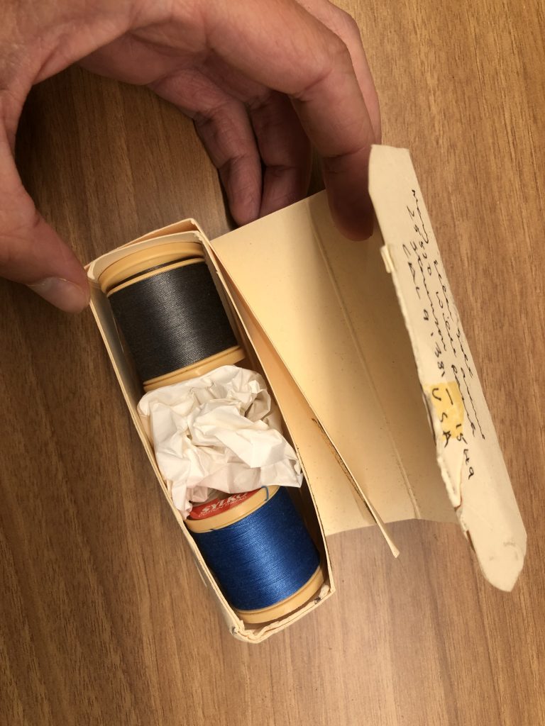 Photo of a box opened to reveal that it contains two spools of thread.
