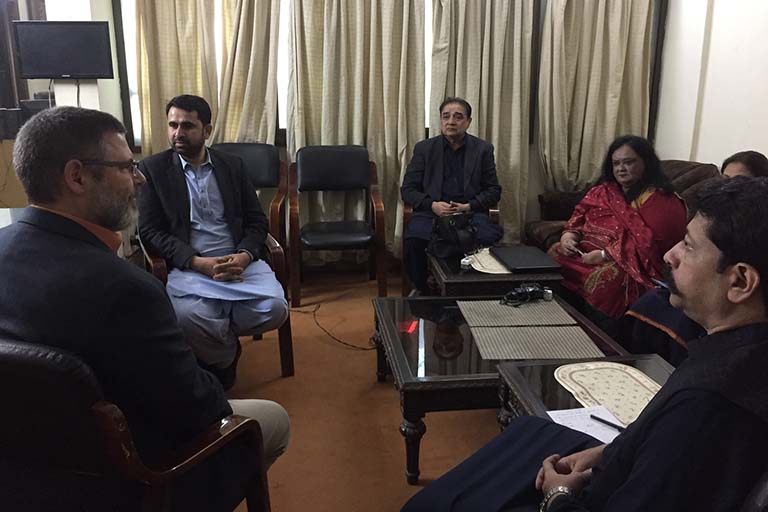 Alan Burdette sitting and talking with the staff at Radio Pakistan Multan.