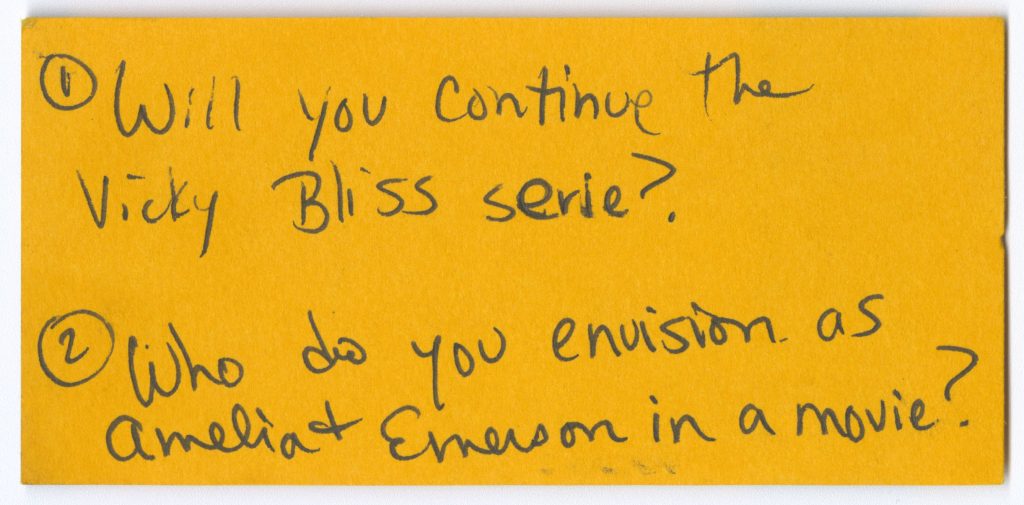 Small yellow stub with the following text handwritten: “1) Will you continue the Vicky Bliss serie? 2) Who do you envision as Amelia and Emerson in a movie?”