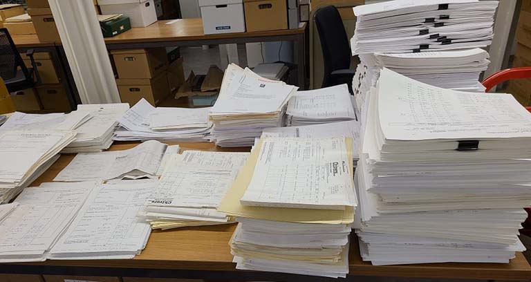 Stacks of papers in piles of varying sizes spread out on a large table