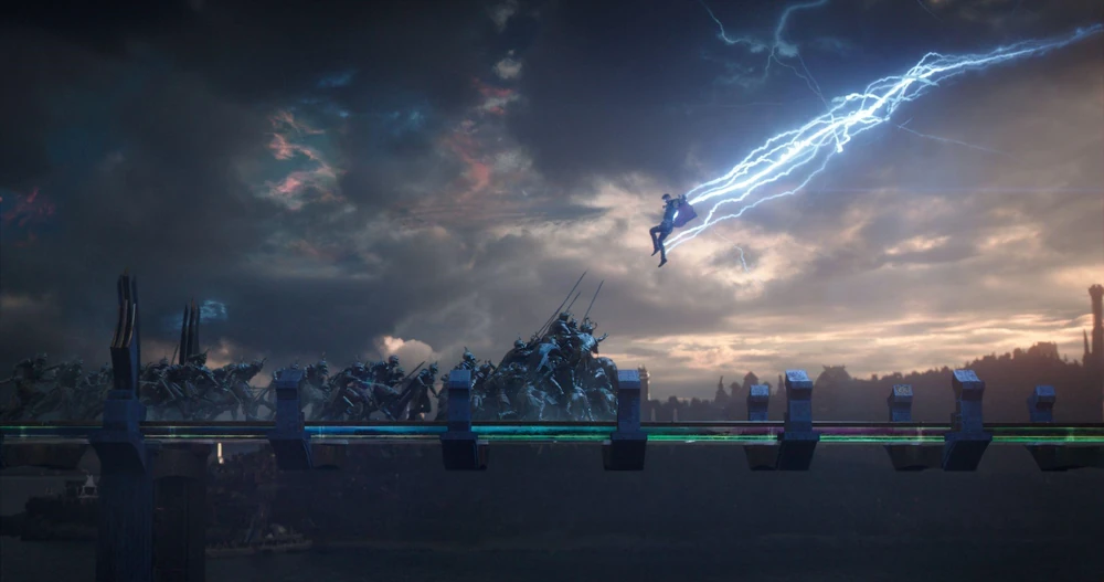 Scene from Thor: Ragnarok (2017): A superhero soars through the sky, bathed in lightning, while a vast army of enemy troops gathers on Earth below.