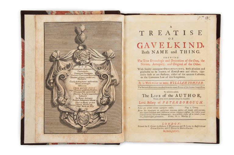 Two-page spread of frontispiece ornamental shield bearing text with  title page in red and black print. 
